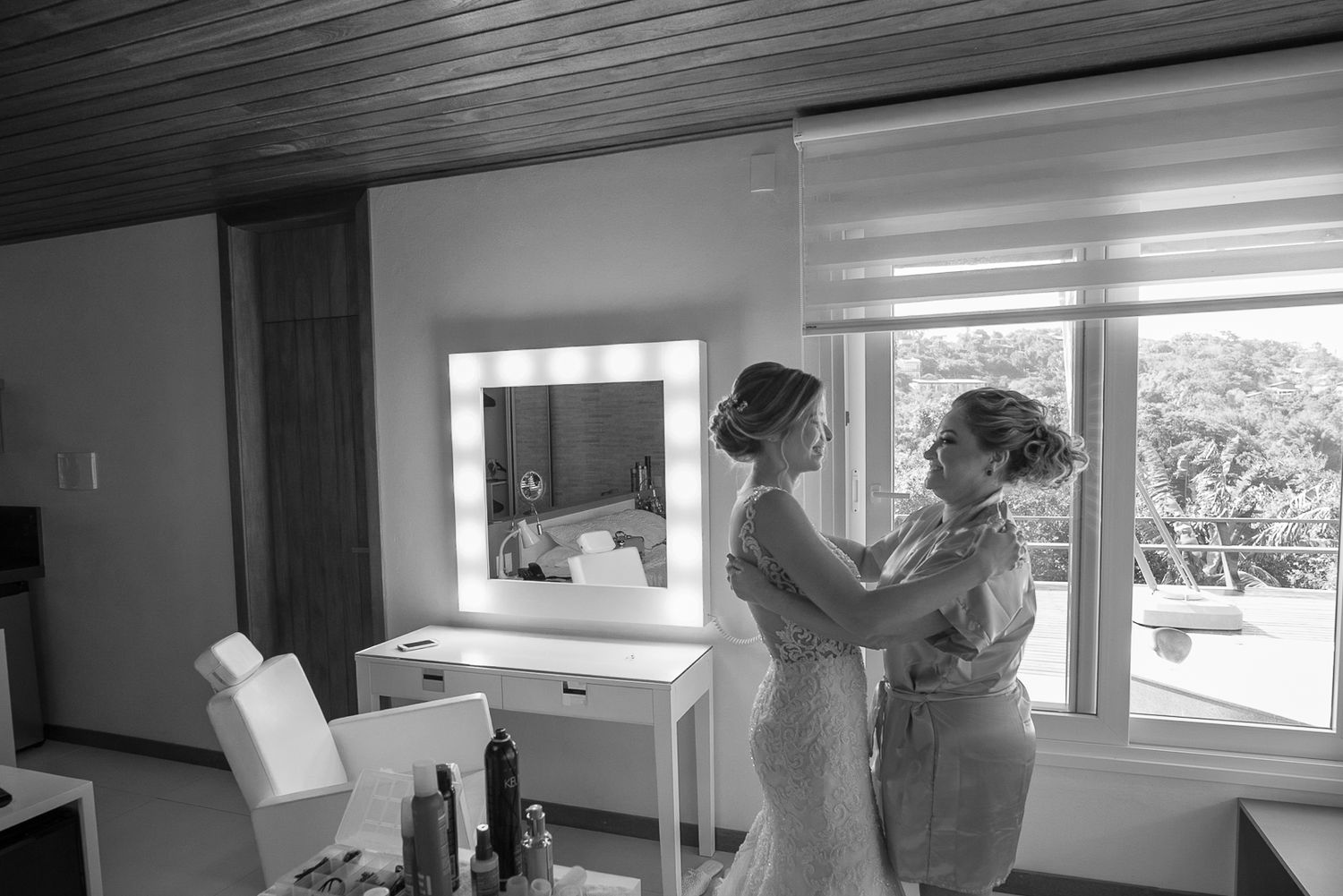 Black and white photo showing intimate moment in preparation room with makeup vanity.