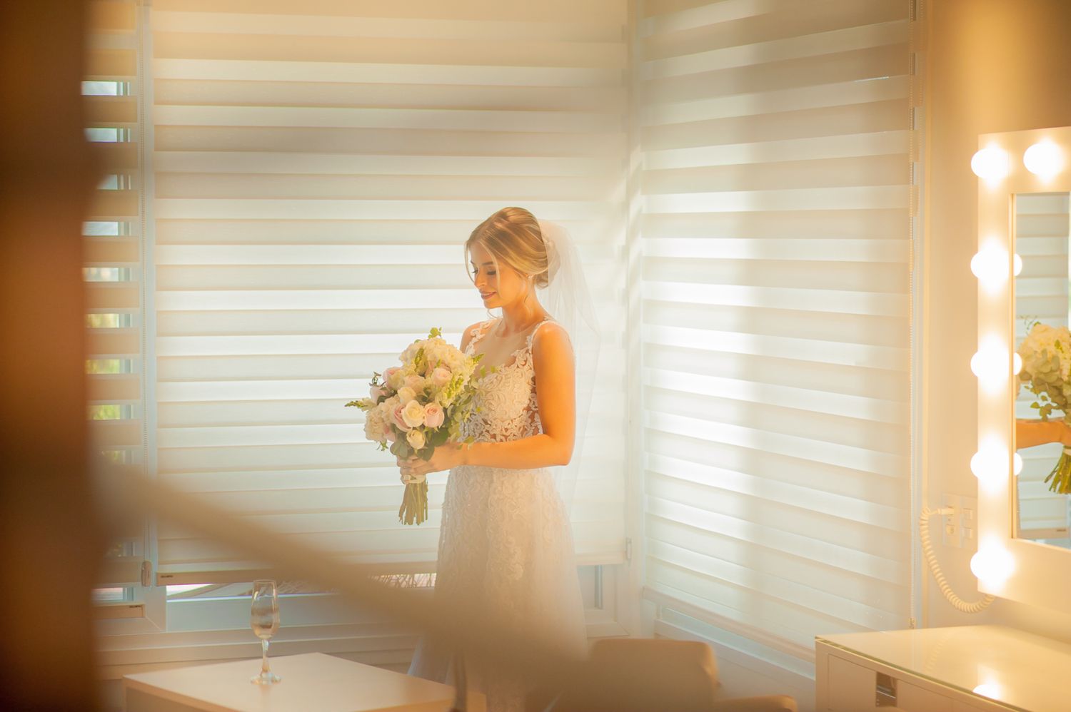 Soft focus artistic portrait of bride holding bouquet near makeup vanity.