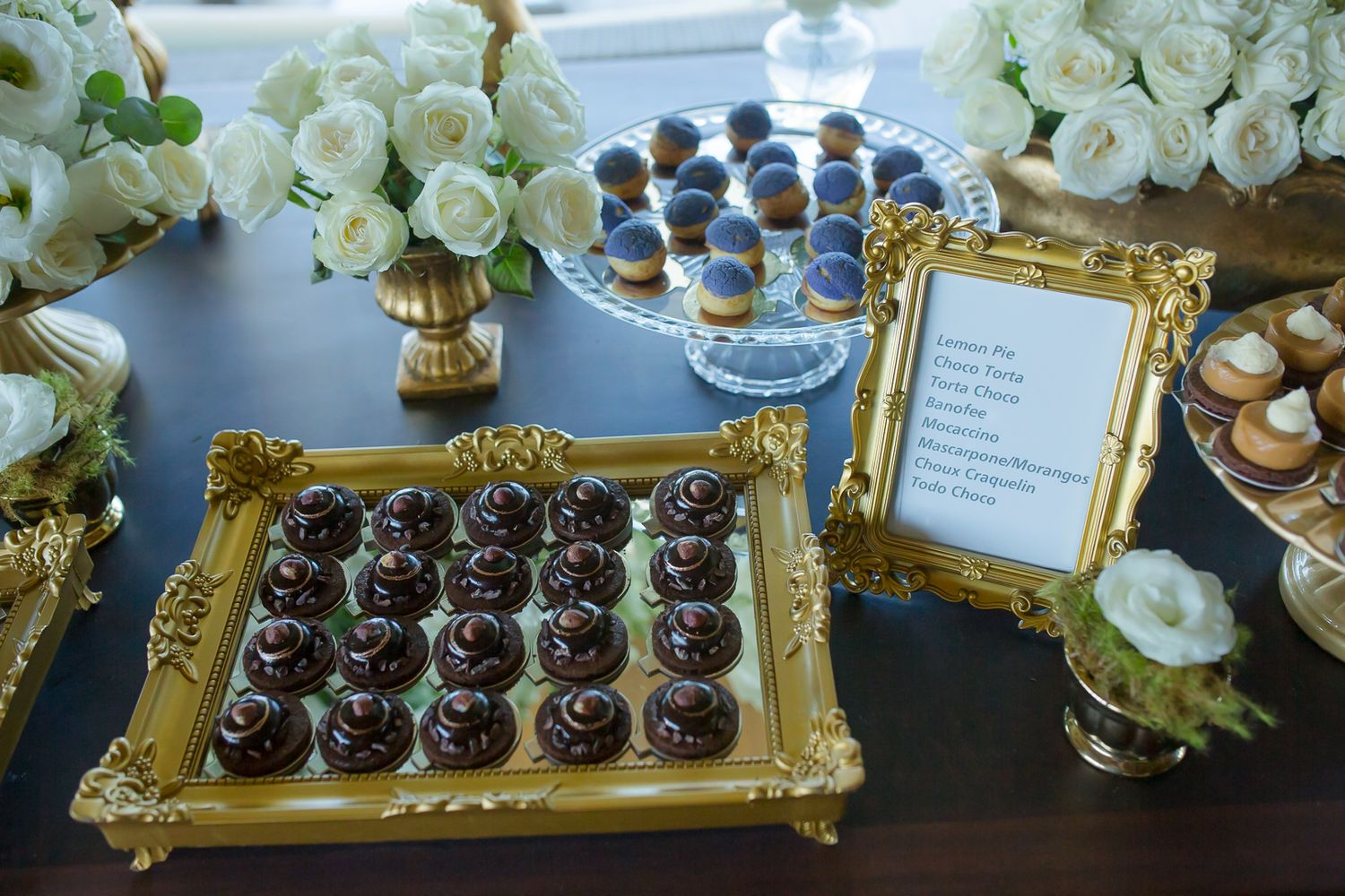 Luxurious dessert display with gold frames, white roses and chocolate treats.