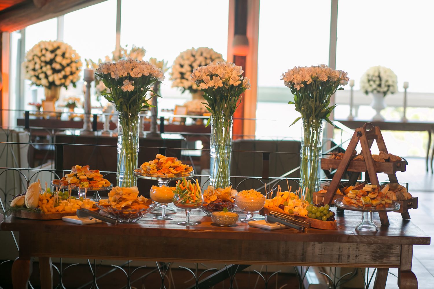 Elegant wedding reception table decorated with tall orange flower arrangements and glass vases.