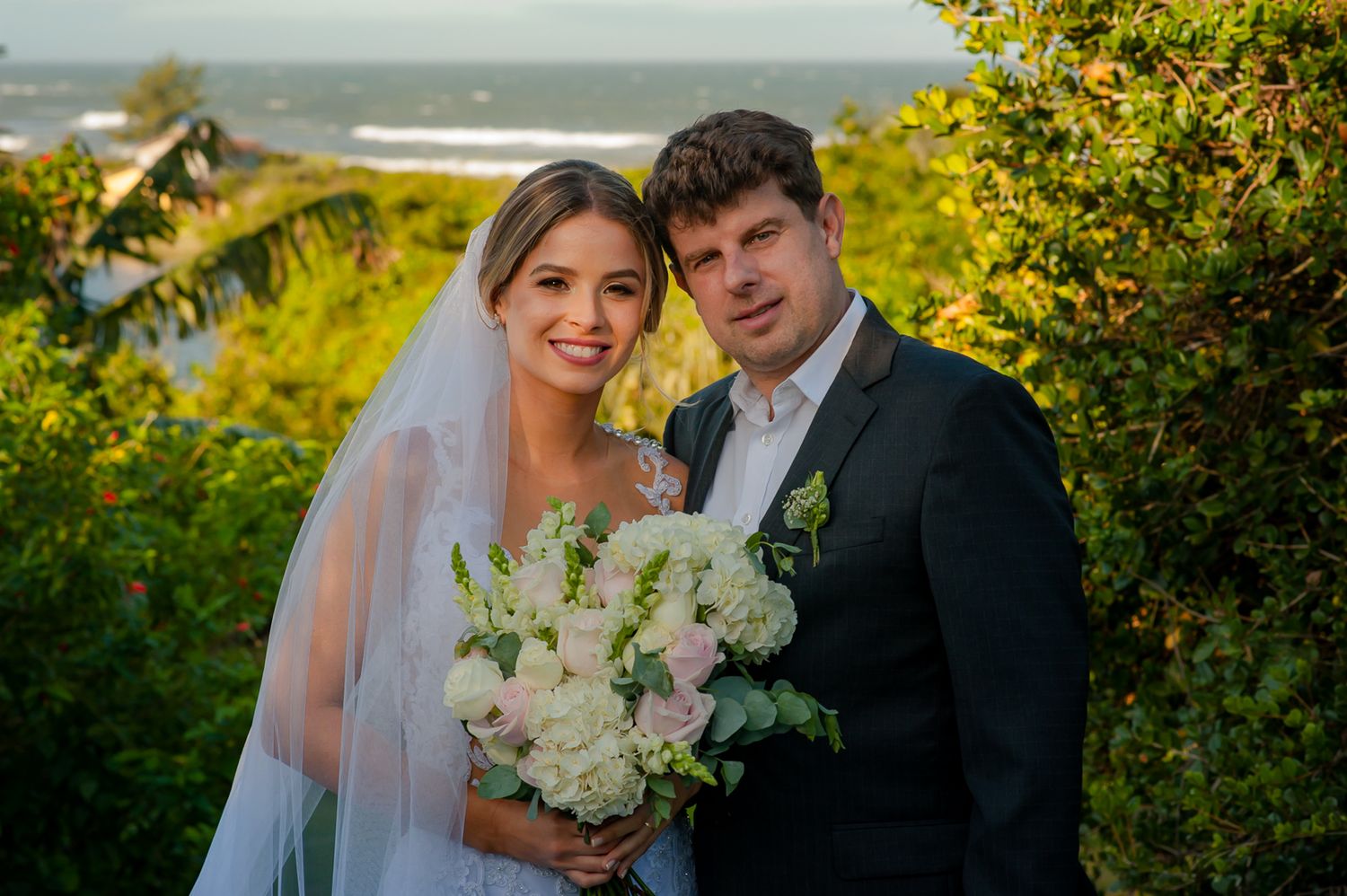 Coastal wedding portrait with sweeping ocean views and natural foliage.