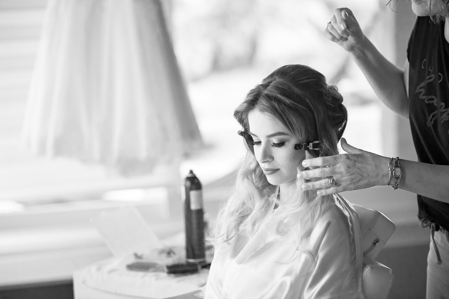 Black and white photo of wedding preparations in a bright room with styling taking place.