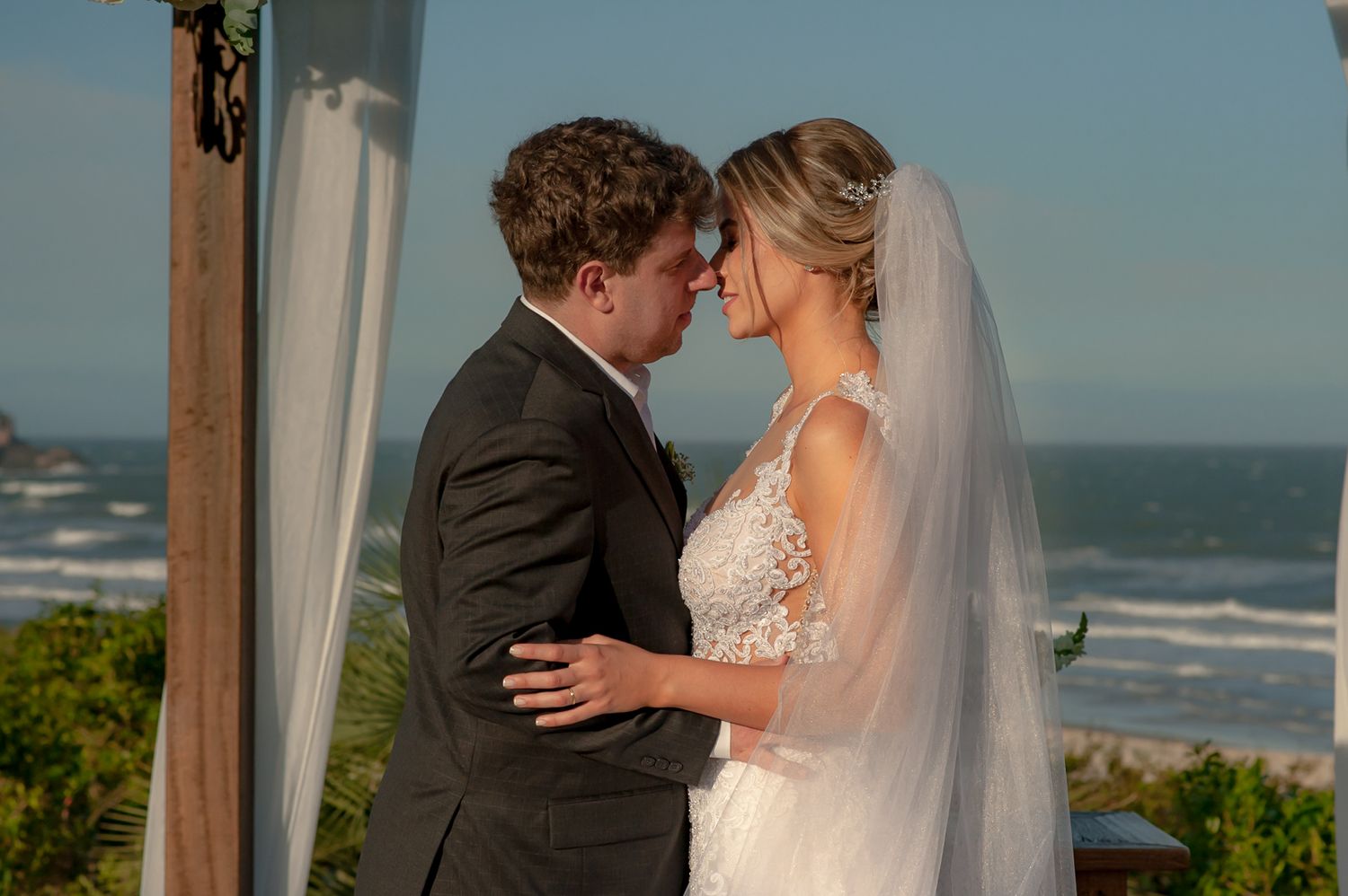 Romantic moment between newlyweds at oceanfront wedding ceremony site.