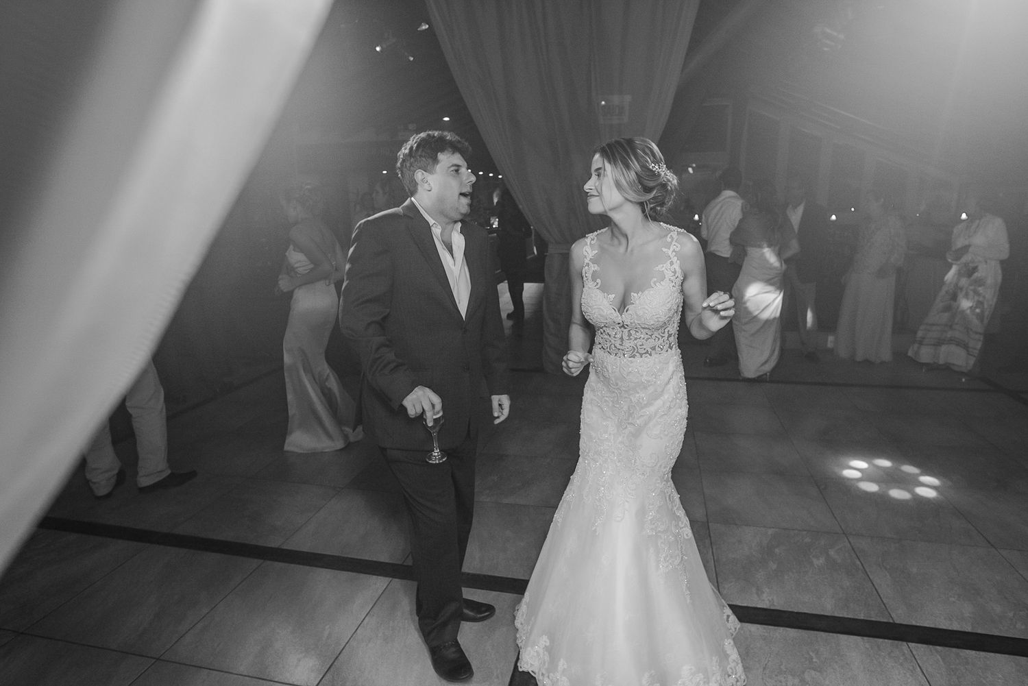A couple sharing a romantic dance moment on the reception floor in black and white.