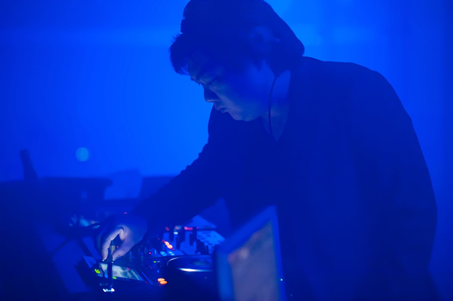 A DJ performing in dramatic blue lighting at a nightclub or event.