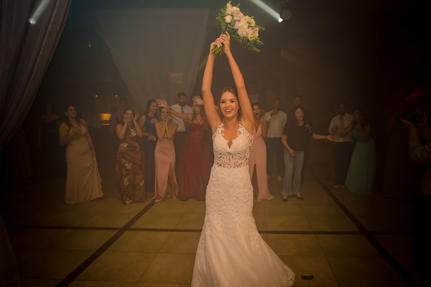 A celebratory moment during a wedding reception with spotlights and crowd in background.