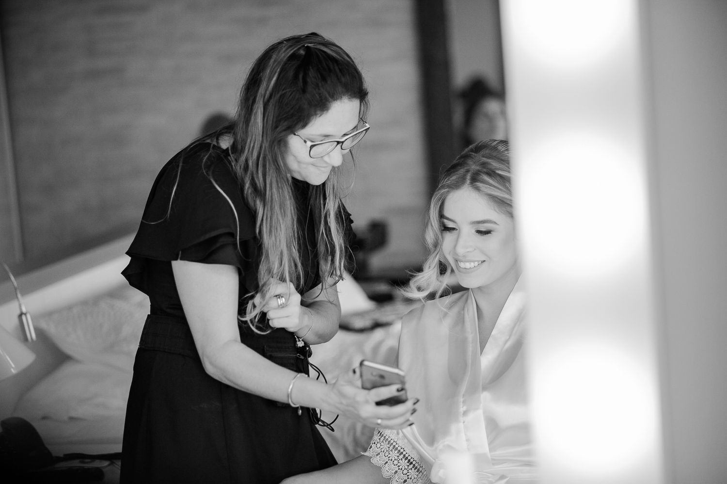 Black and white image showing final wedding day preparations in an interior setting.