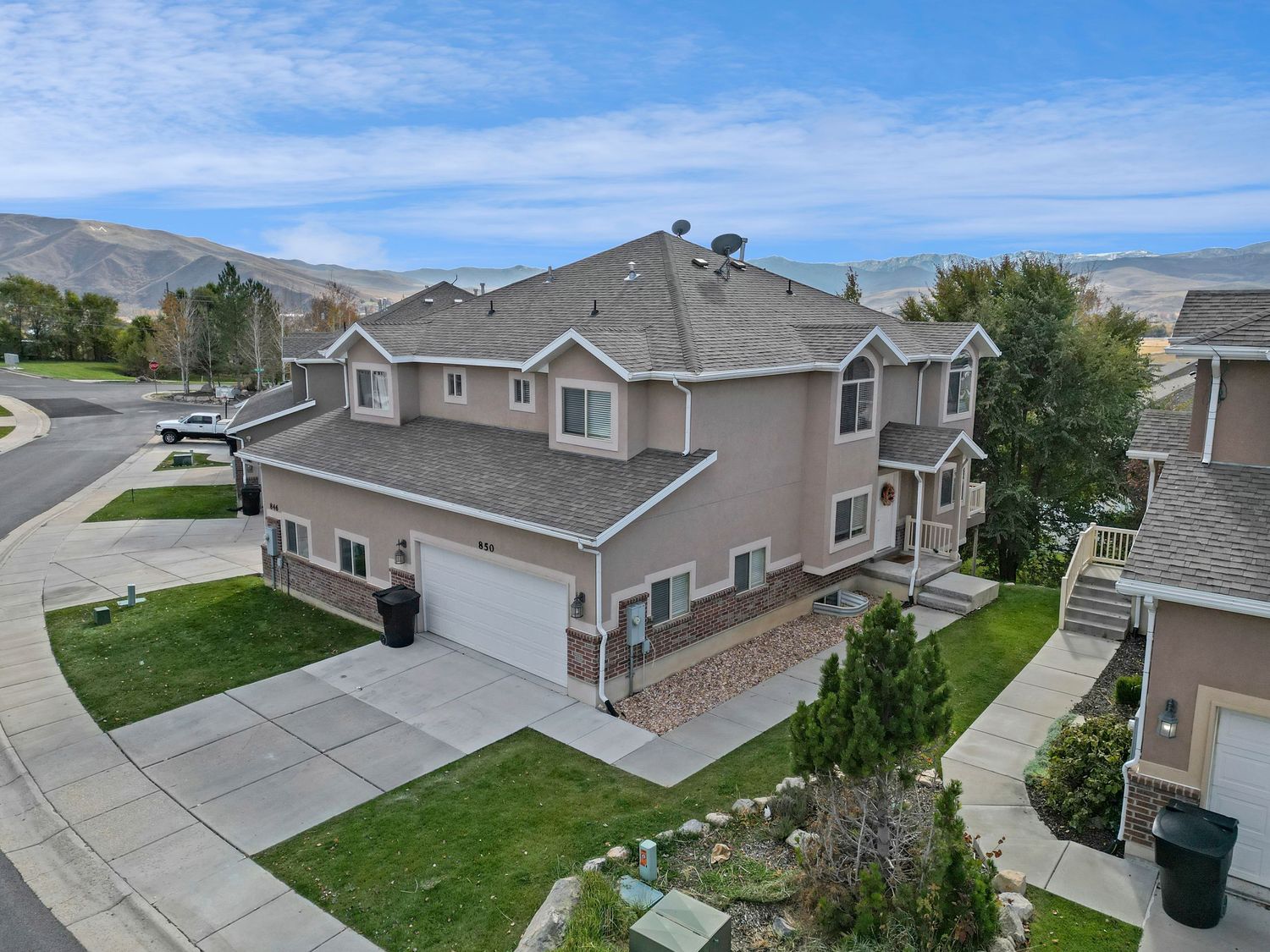 Large two-story stucco home with two-car garage, mountain views, manicured landscaping, and corner lot placement.
