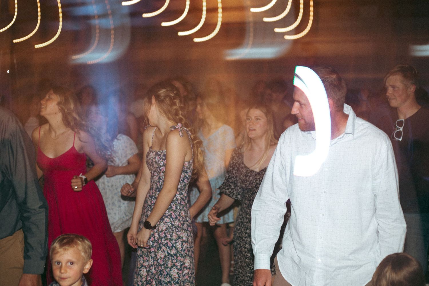 A blurred motion shot of wedding guests dancing with light trails creating an artistic effect.