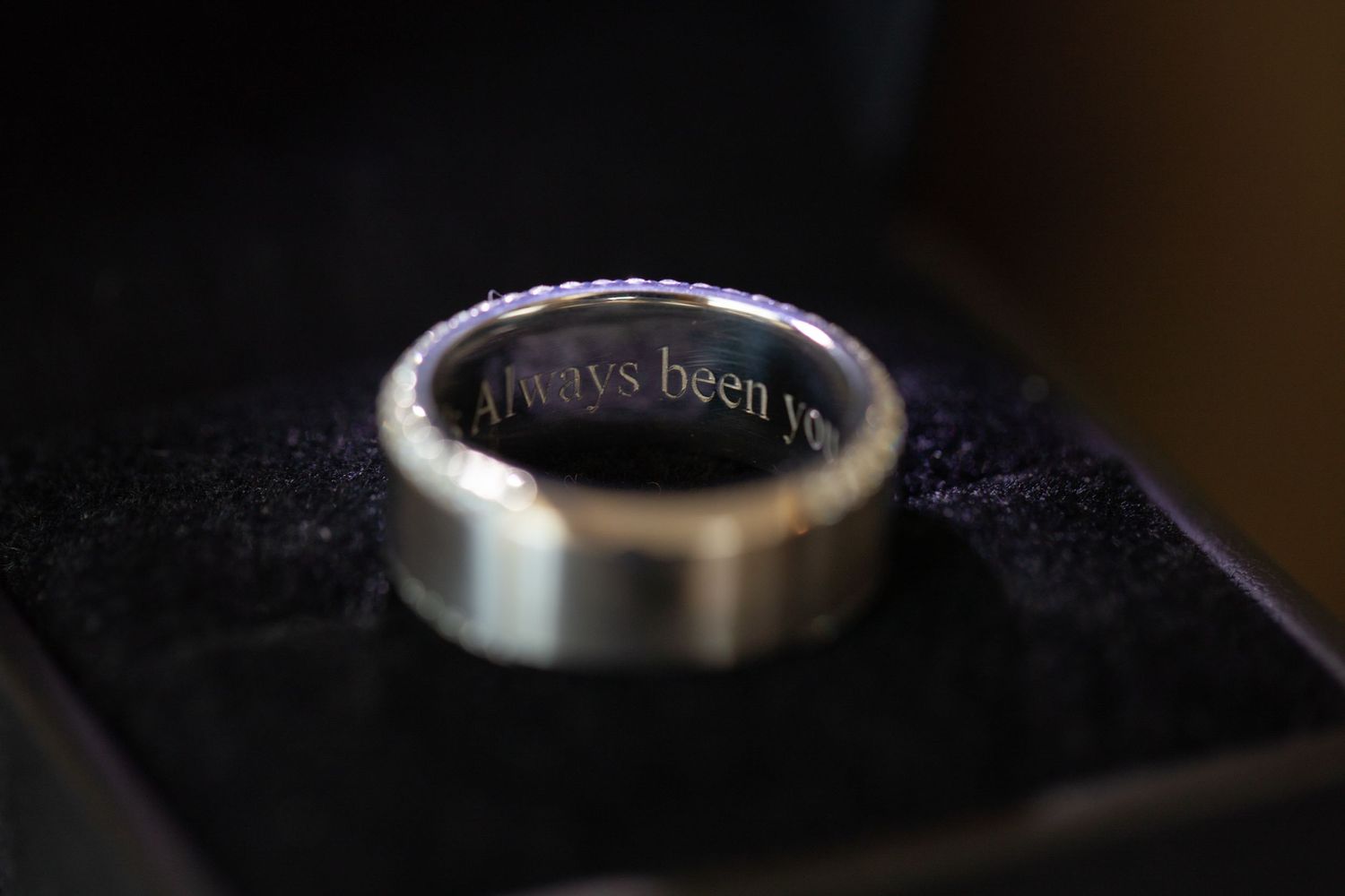 Close up detail shot of engraved silver wedding ring on dark background.