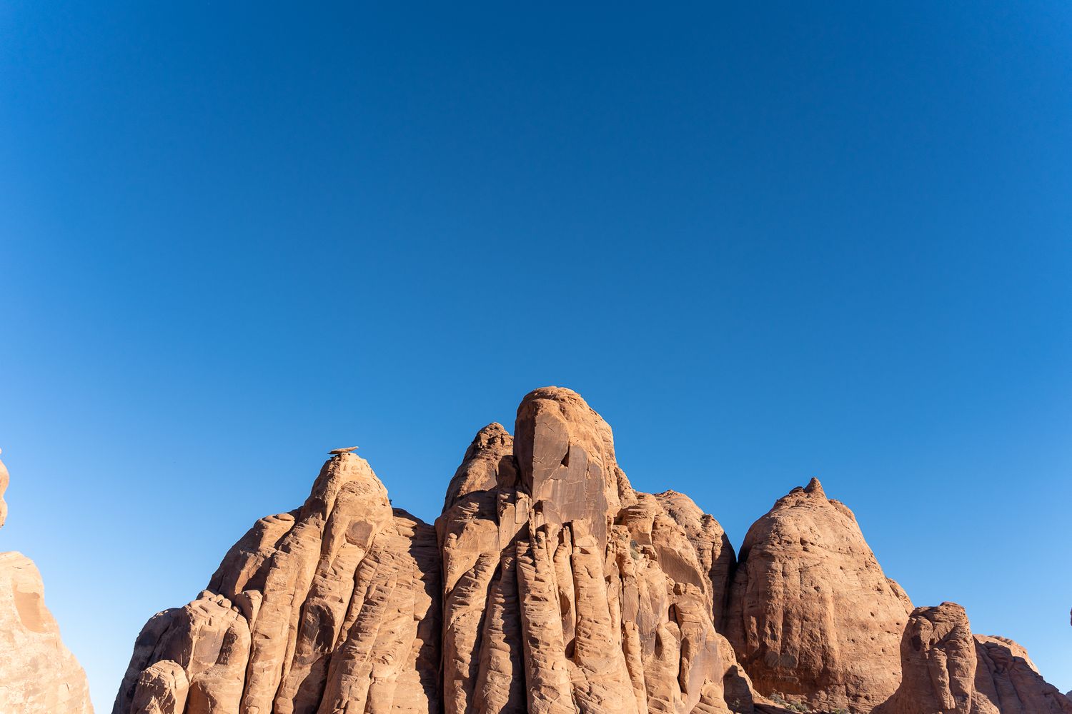 Towering red rock formations against clear blue sky in desert landscape.