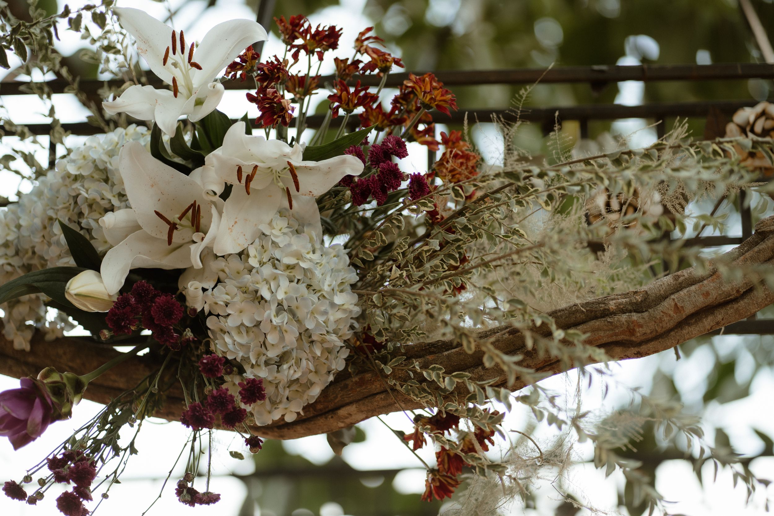 Beautiful wedding floral arrangements with white and burgundy blooms hanging from above.