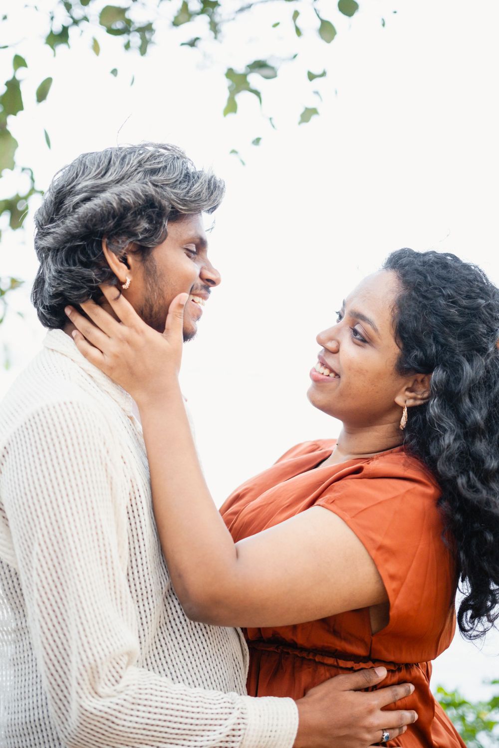 A romantic couple embraces under trees with soft lighting creating an intimate moment.