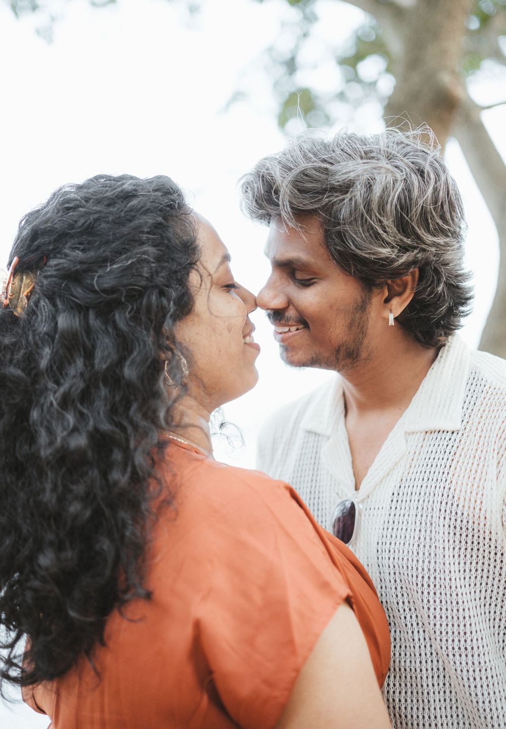A couple shares an intimate close-up moment outdoors with soft natural lighting.