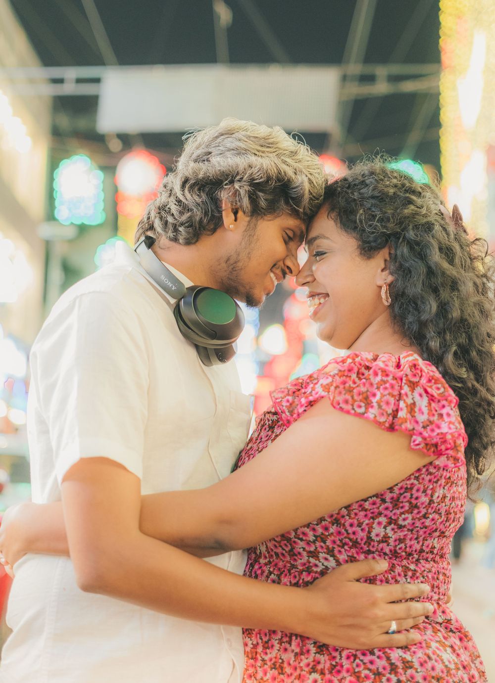 A couple shares an intimate moment in an indoor setting with colorful ambient lighting.