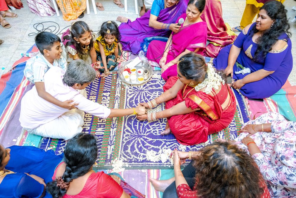 People in colorful traditional Indian attire sitting on the ground playing a board game together.