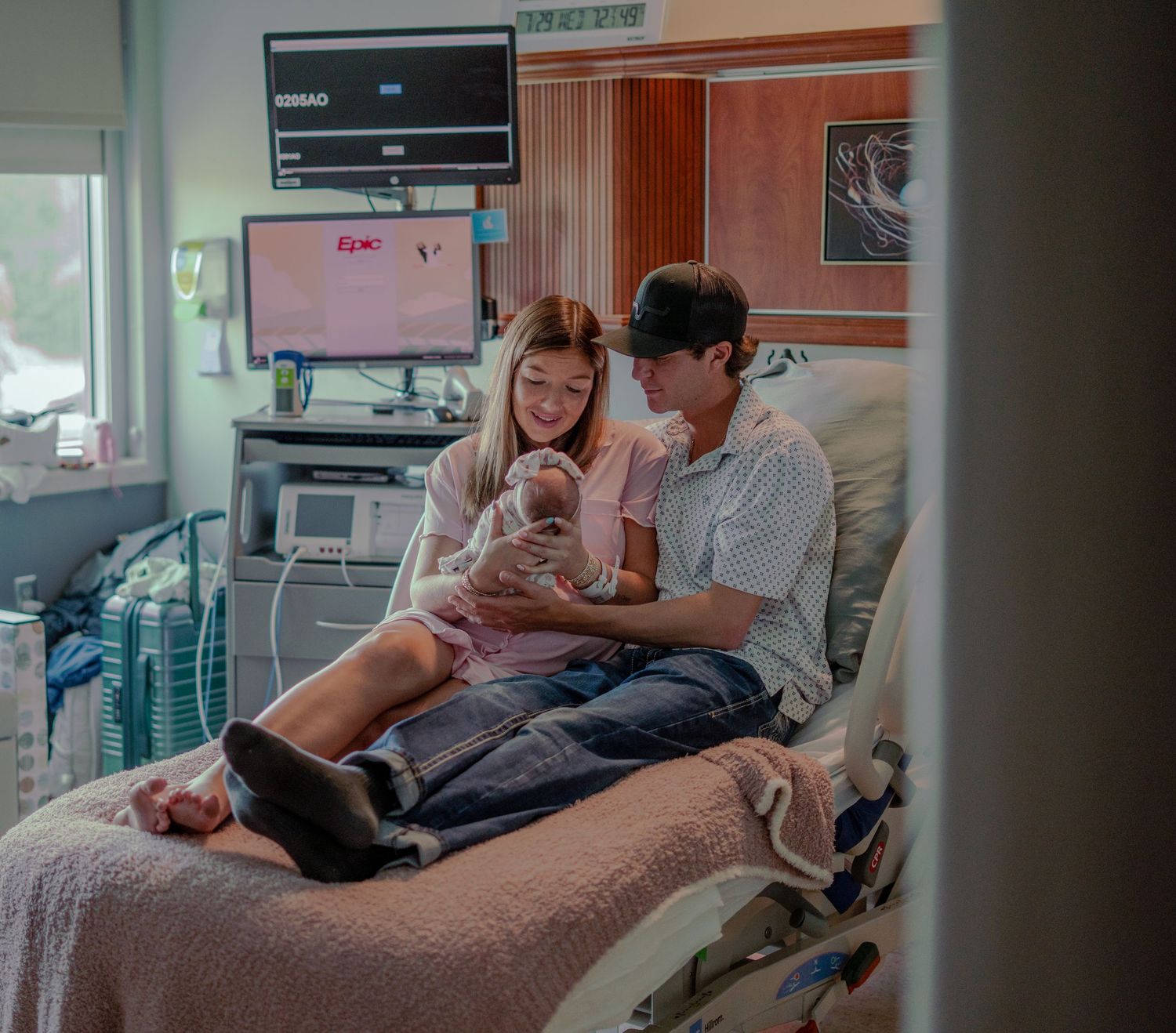 Young couple in hospital room admiring their newborn baby together.