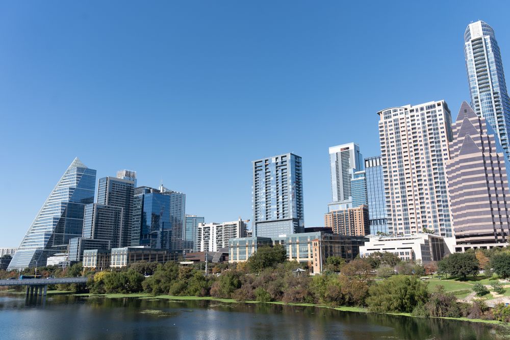Modern Austin skyline with glass skyscrapers reflecting in Lady Bird Lake on a clear sunny day.