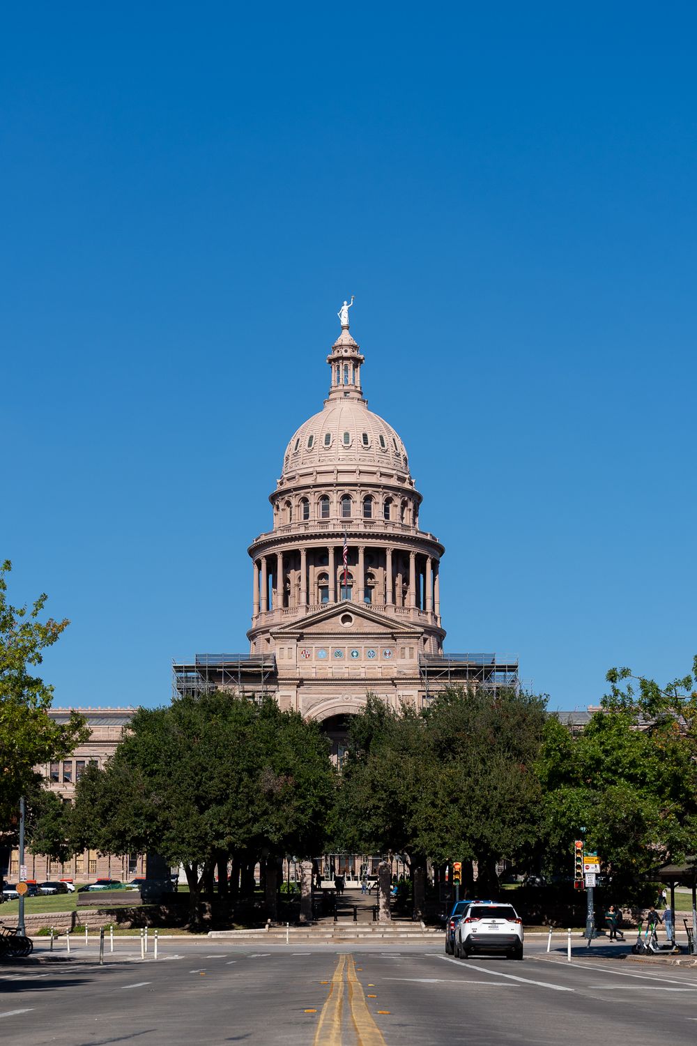 Texas State Capitol building dome rising above trees on a bright sunny day in Austin.