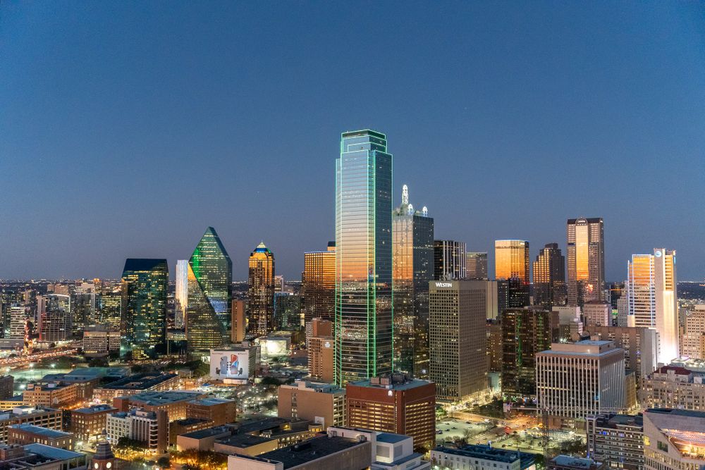 Illuminated Dallas skyline at dusk showcasing iconic buildings and architecture.