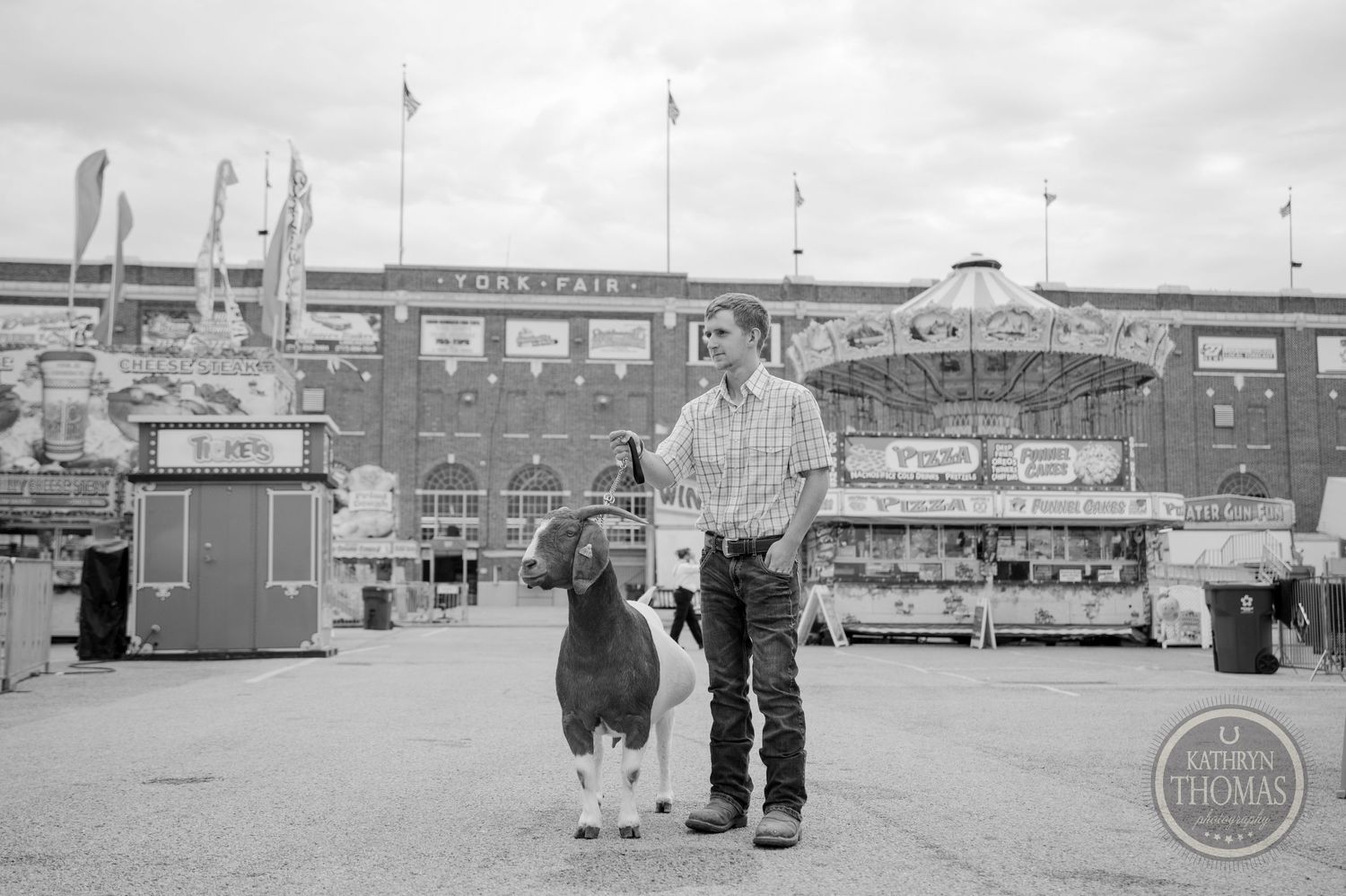 A black and white photo of a dairy cow and handler at a vintage fairground.
