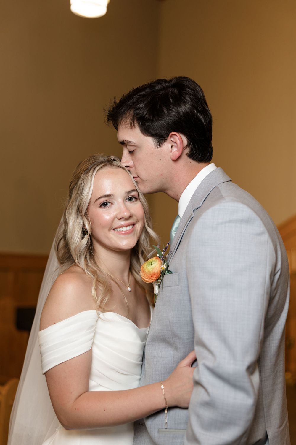 A romantic first look moment captured in an indoor setting with soft lighting and warm tones.