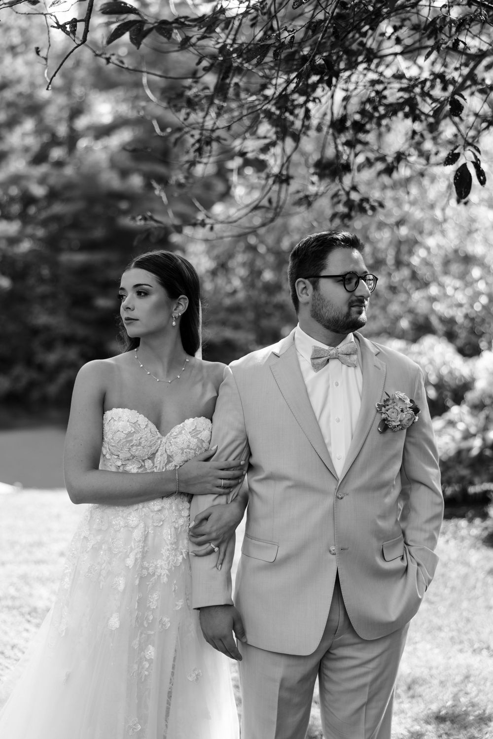Romantic black and white wedding photo of newlyweds walking together through a blooming garden.