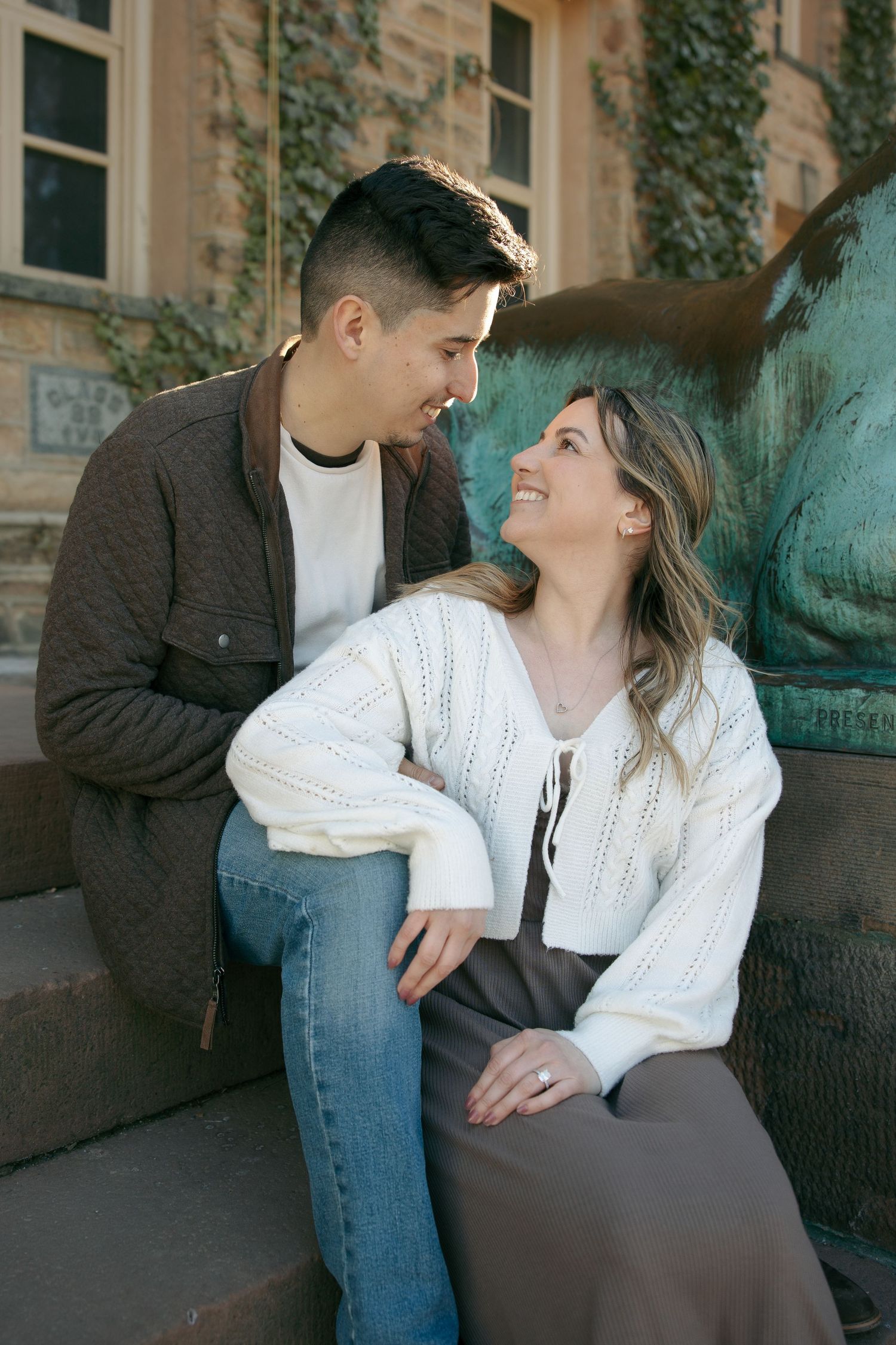 Couple in casual fall outfits sharing a romantic moment while holding hands in an autumn park setting.