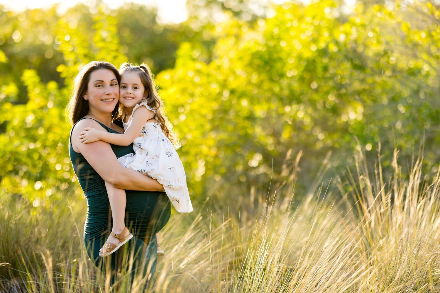 Candid family moment captured in a sun-drenched meadow with vibrant yellow foliage.