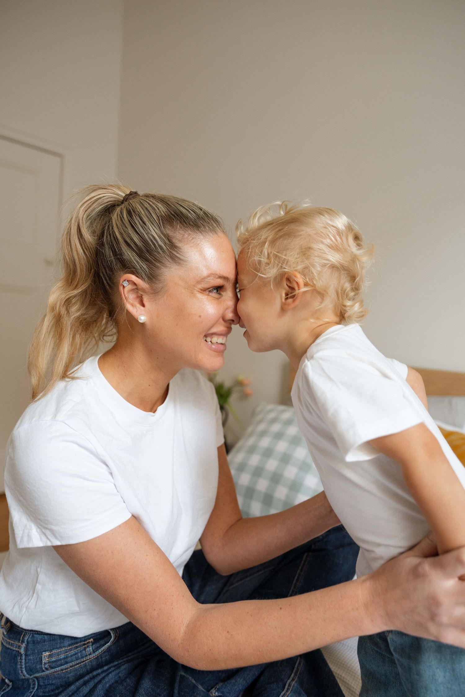A mother and her son having fun together, putting their heads together and smiling.