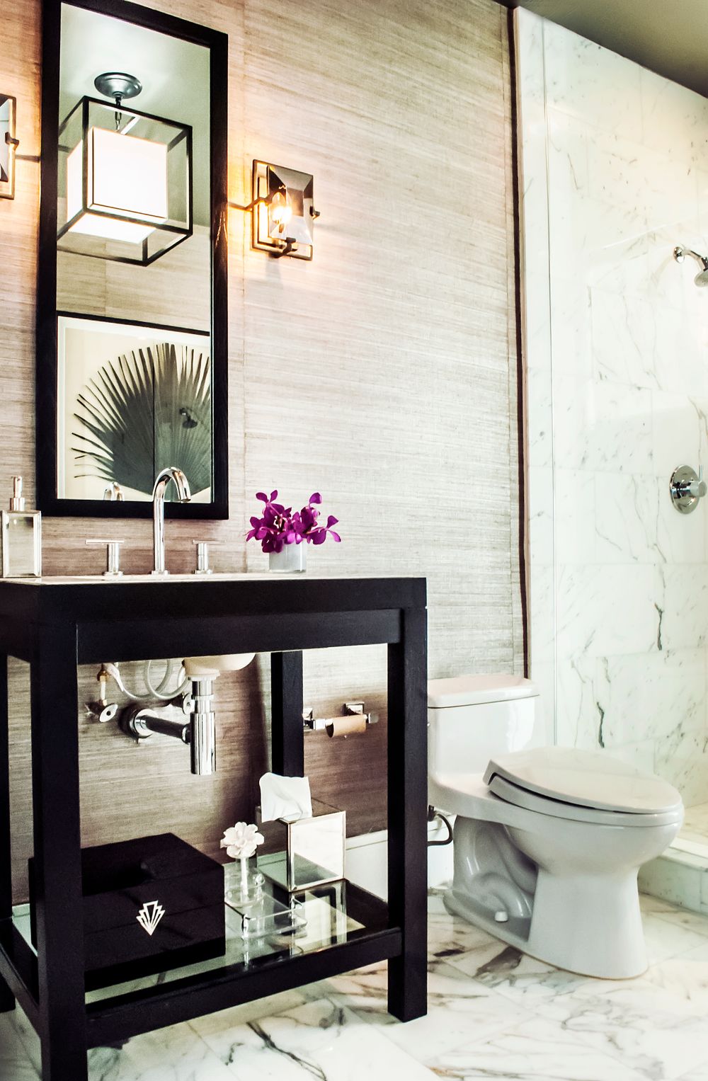 Elegant bathroom with black vanity, square lantern sconce, and textured wallpaper accents.