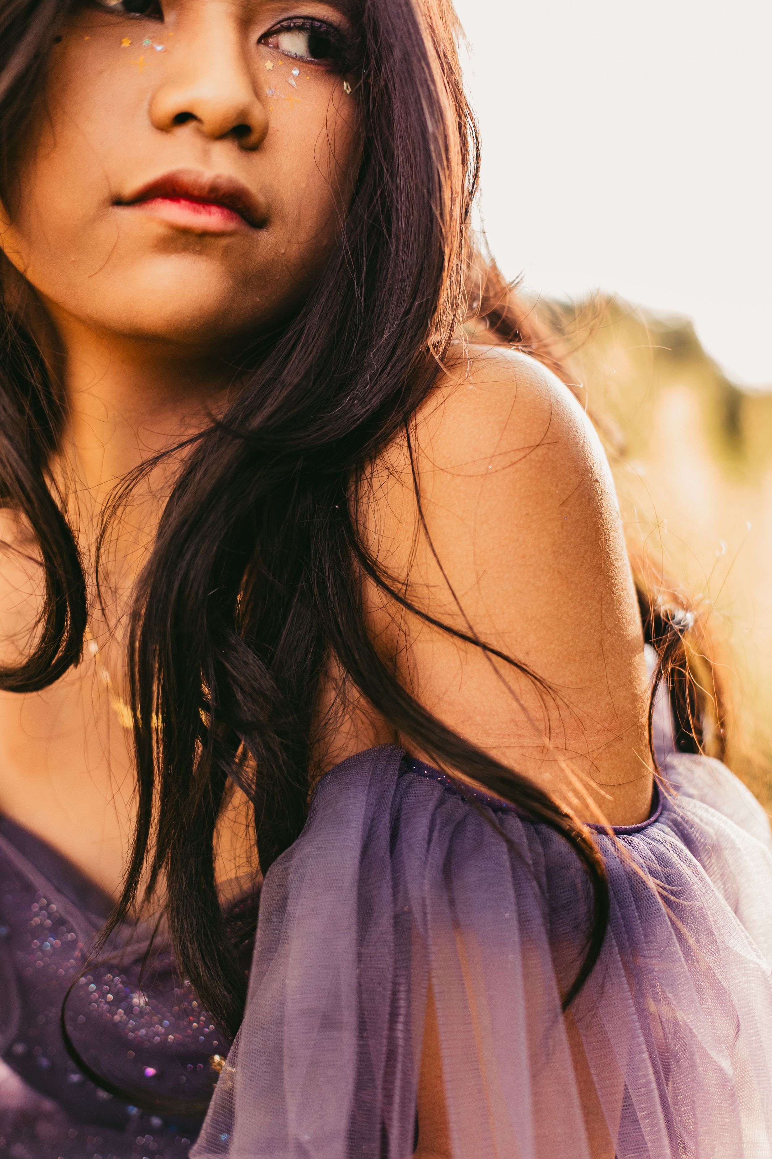 A series of five cropped portraits showing a person with dark hair in a purple tulle dress against a warm sunset background.