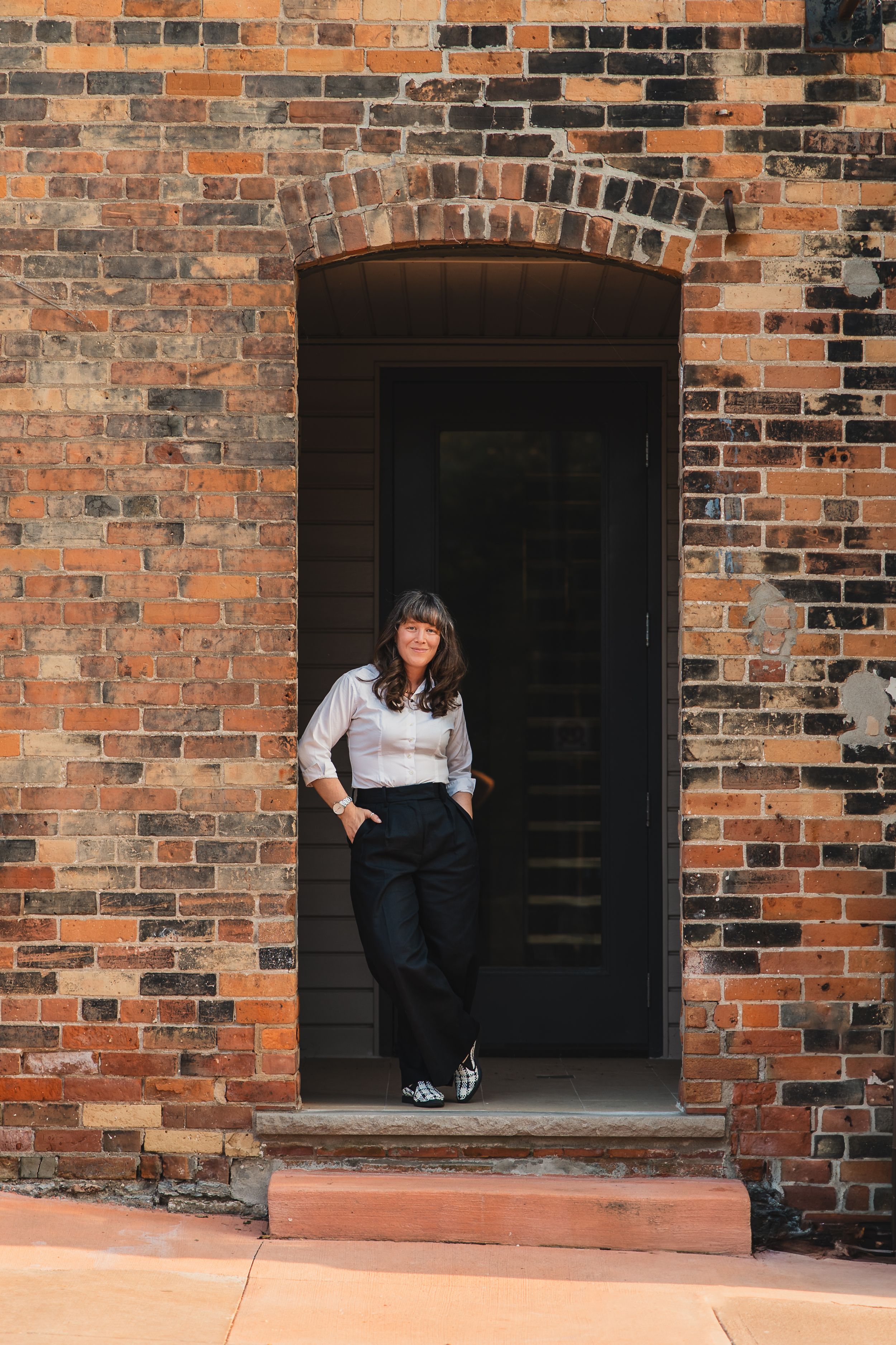 Four sequential photos showing someone standing, sitting and crouching in different poses against a rustic brick wall with dark doorways.