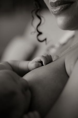 Black and white photo of a mother breastfeeding her newborn baby, capturing a tender and intimate bonding moment.