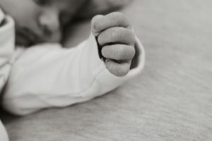 Close-up black and white photo of a newborn baby's tiny clenched fist.