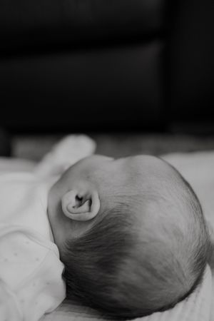 Black and white close-up portrait of a sleeping newborn baby's head and ear.