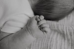 Black and white macro photo of a newborn baby's tiny clenched fist.