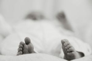 Black and white close-up of newborn baby feet on soft white blanket.