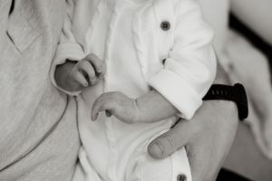 Black and white photo of a newborn baby being cradled in an adult's arms.