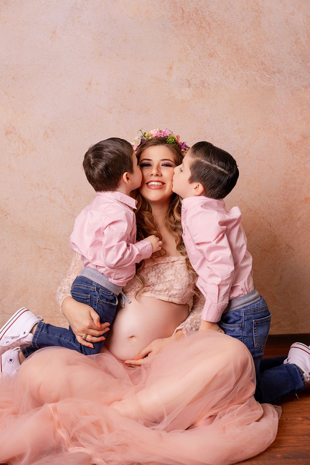 A maternity photo series shows tender moments in a pink tulle dress with matching outfits.