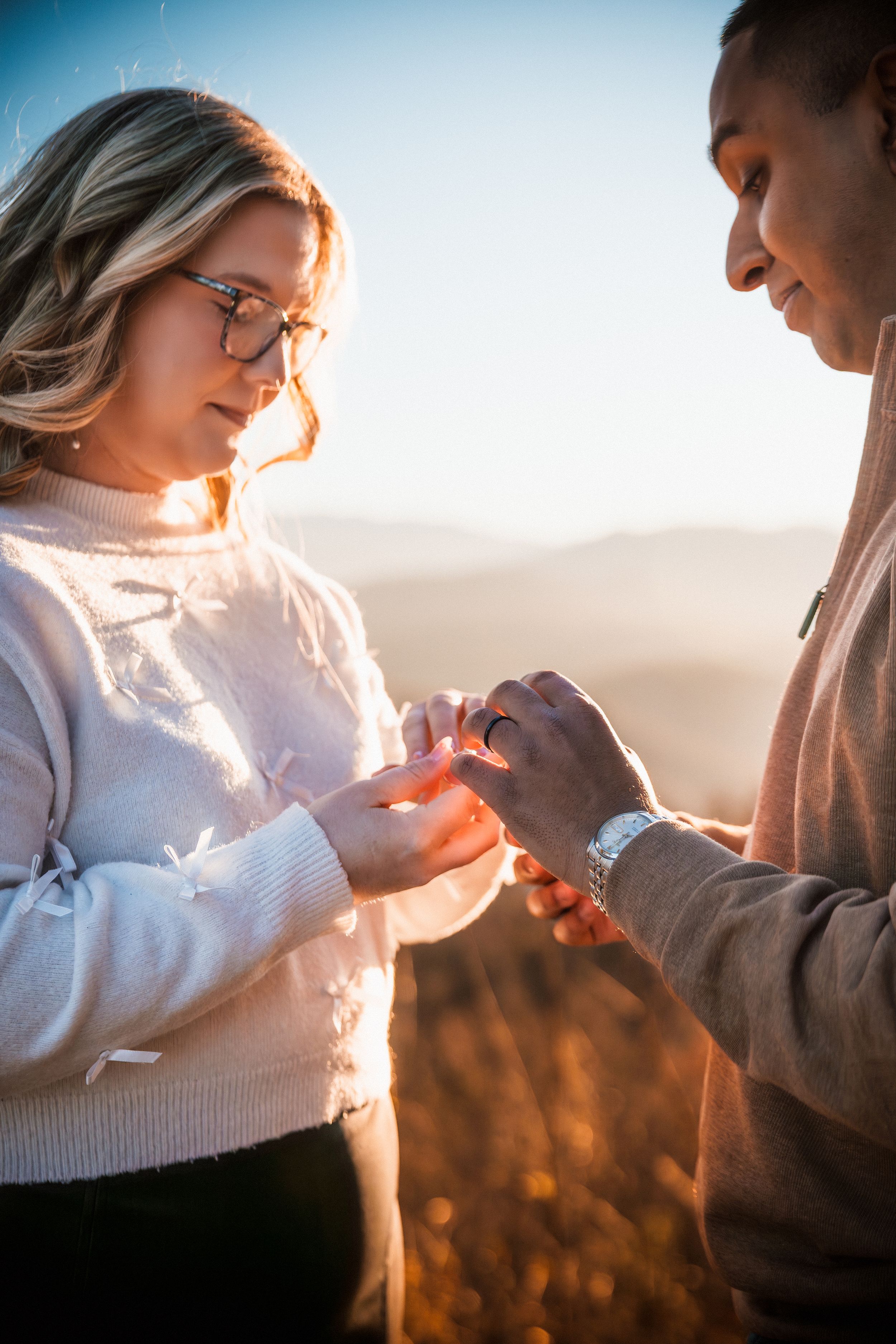 A romantic proposal moment captured during golden hour as a couple exchanges a ring outdoors in warm sunlight.