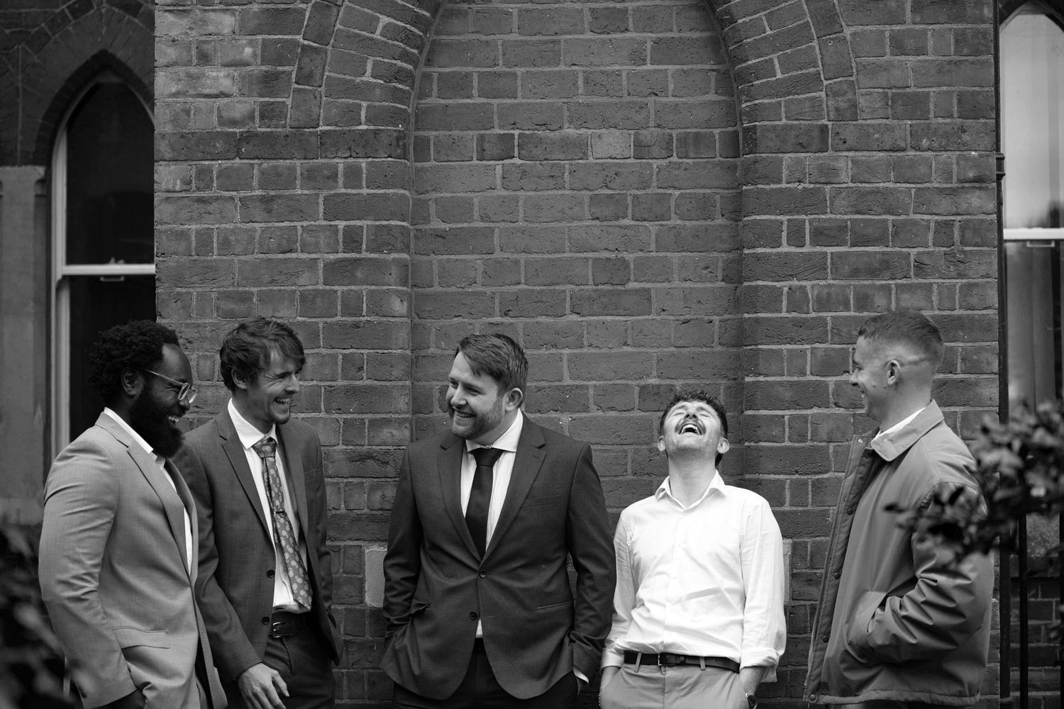 A historic black and white photograph showing a group of people gathered outside a brick building.