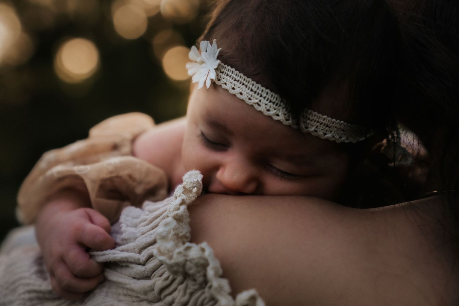 Infant sleeping peacefully beside parent in soft lighting, creating an intimate and tender moment.