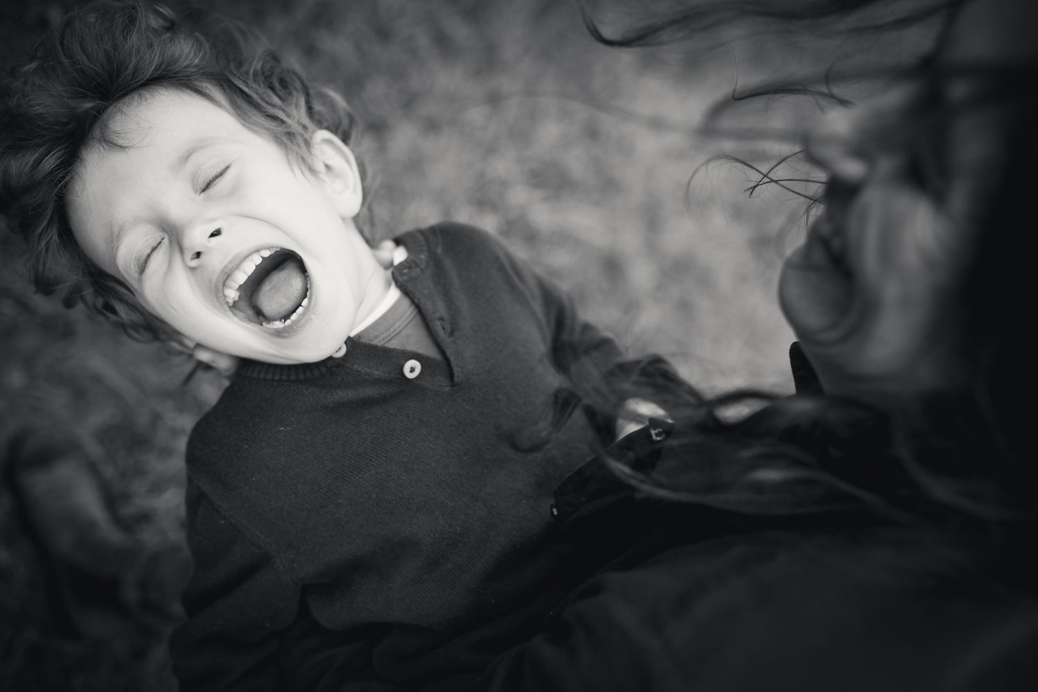 Petit garçon qui éclate de rire dans les bras de sa maman lors d'une séance photo en extérieur à Périgueux