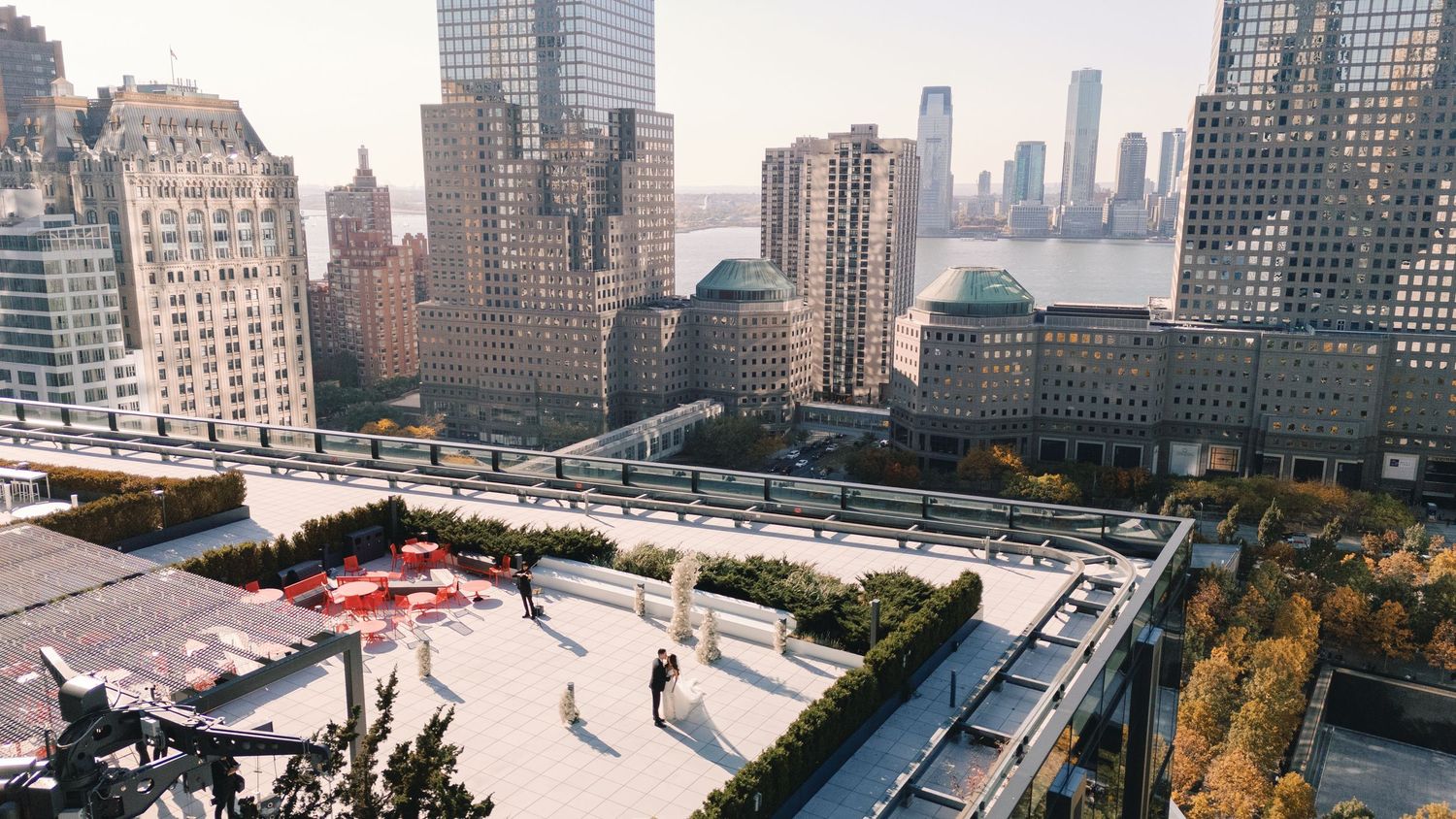 Aerial view of a rooftop wedding venue with city skyline, Hudson River, and lush greenery in New York City.