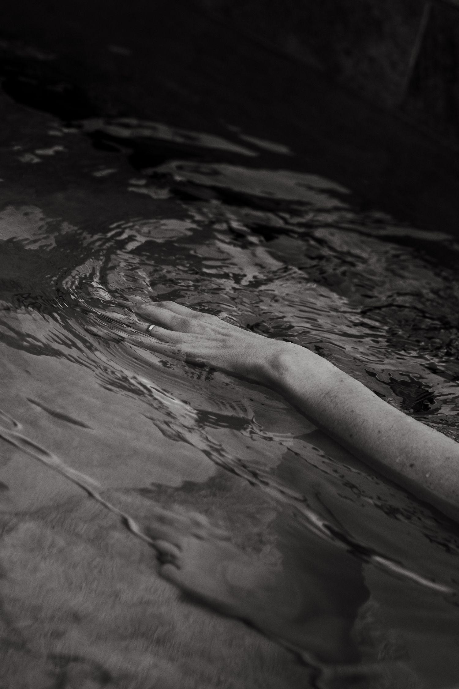 detail of woman's hand touching the surface of water in pool while being captured by yoga photographer in Stockholm