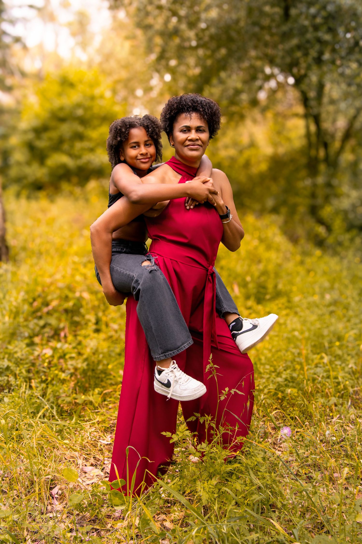 Joyful piggyback ride in a red jumpsuit against autumn foliage.