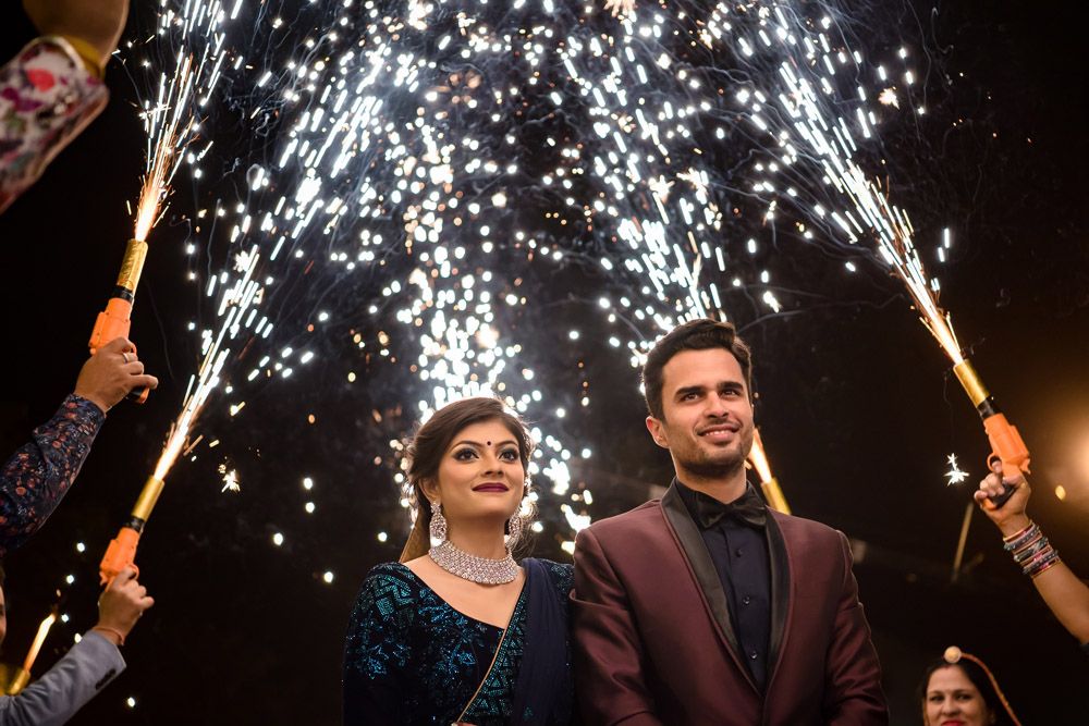 Couple stands beneath spectacular firework sparklers during an evening celebration.