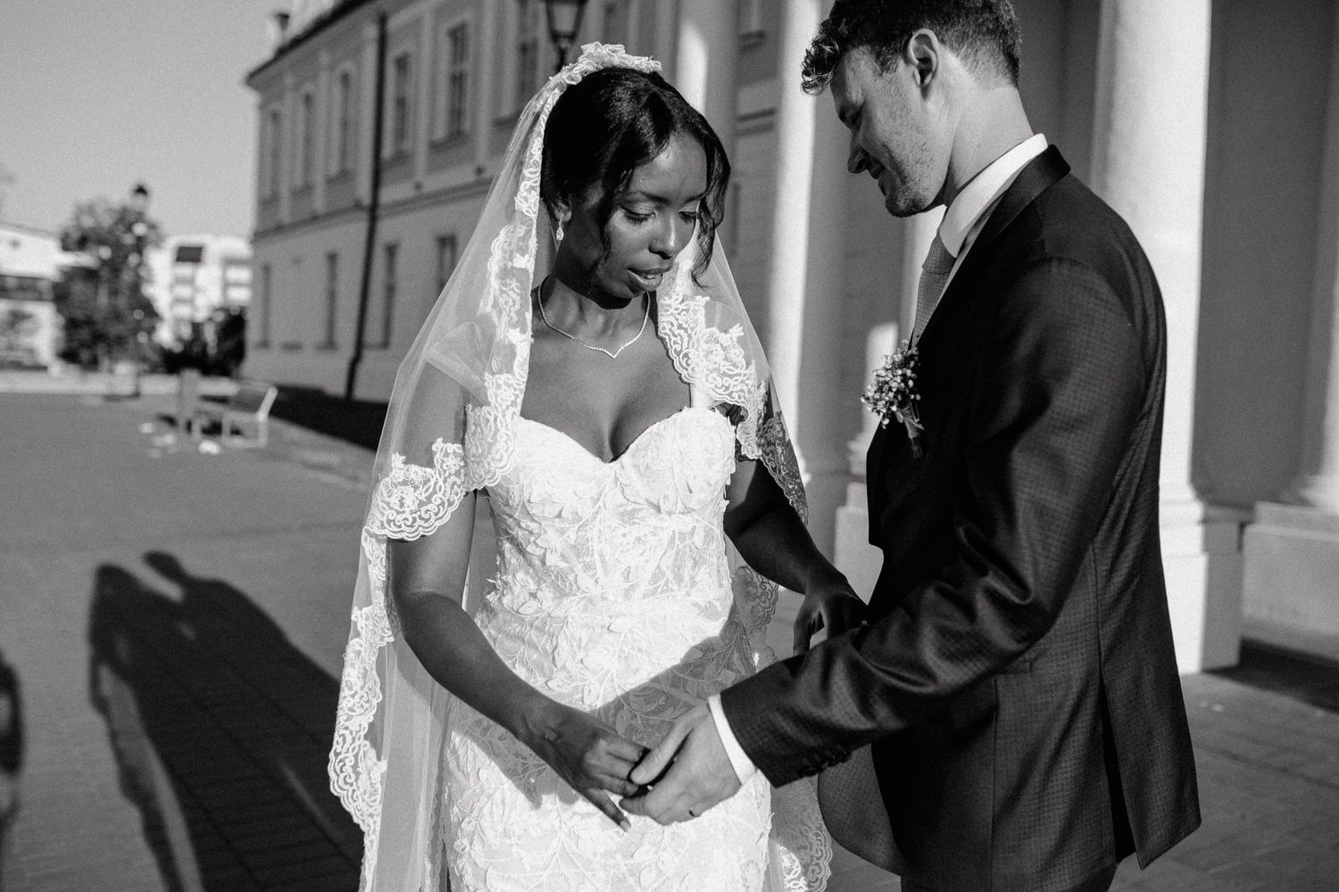A tender black and white wedding moment between a couple in formal attire.