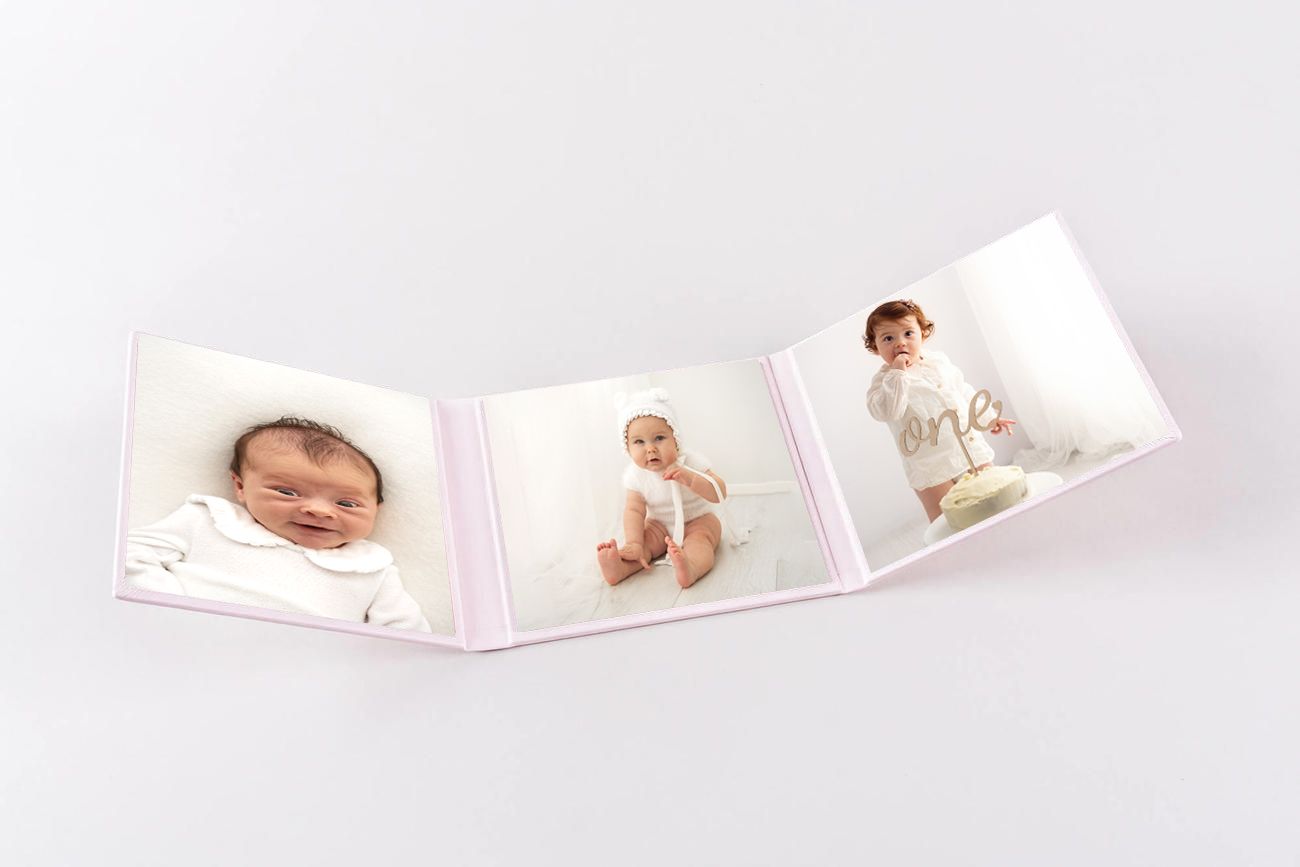 Photo folder holding three images, one newborn baby, one sitting baby and a one year old with birthday cake.